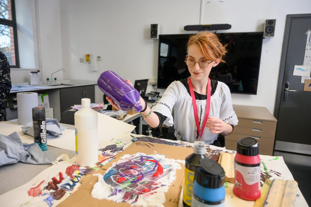 Young girl squeezing paint onto canvas