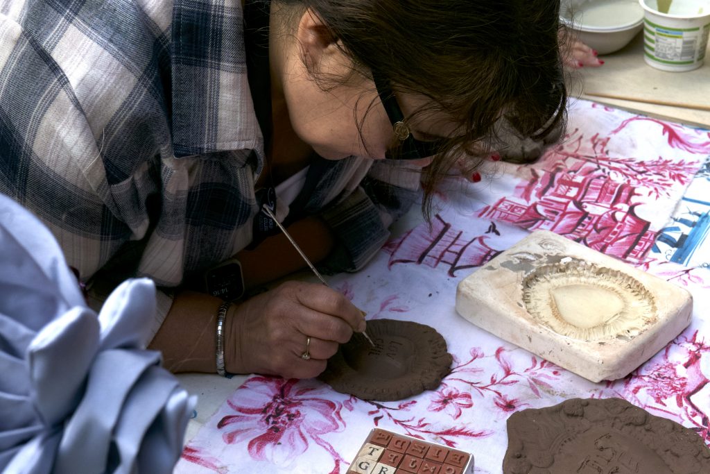 A member of staff creates an image in clay as part of a collection of ceramics to commemorate the Grenfell Tower fire.